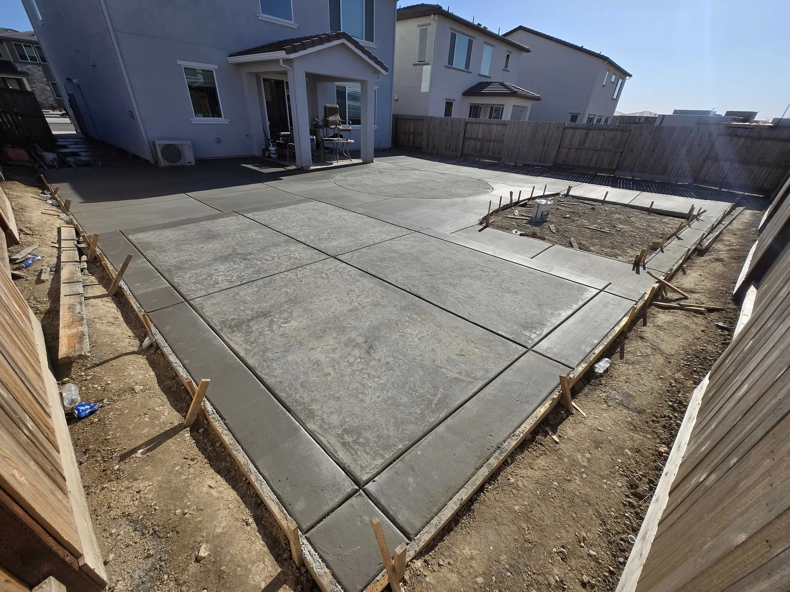 Freshly poured concrete patio slab behind a new-build home