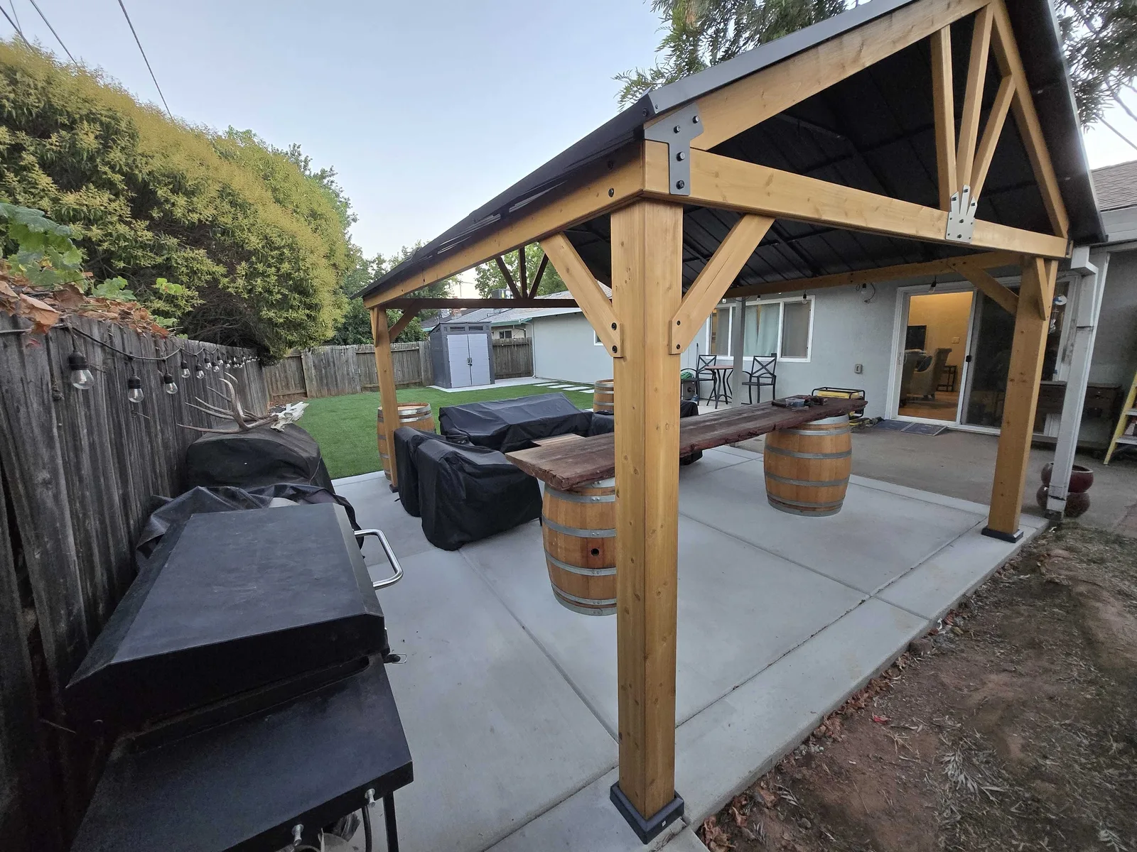 Concrete patio slab under a timber pavilion with an outdoor kitchen