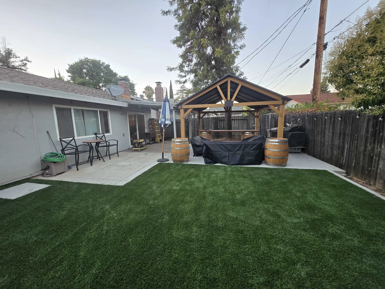 Finished backyard remodel with artificial turf, a concrete patio and a timber pavilion