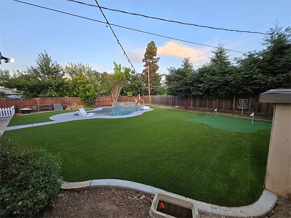 Pool, turf lawn and putting green corner at dusk