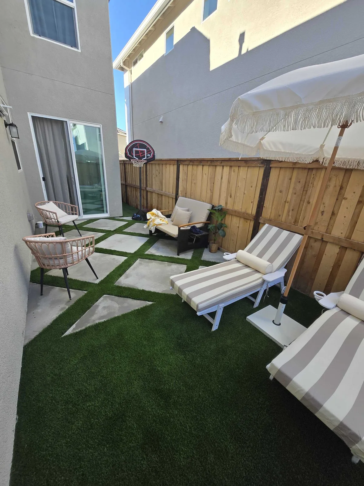 Narrow side yard finished in artificial turf with two lounge chairs