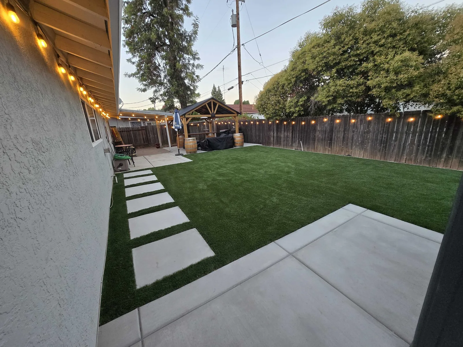 Artificial turf and concrete stepping pads in a backyard at dusk
