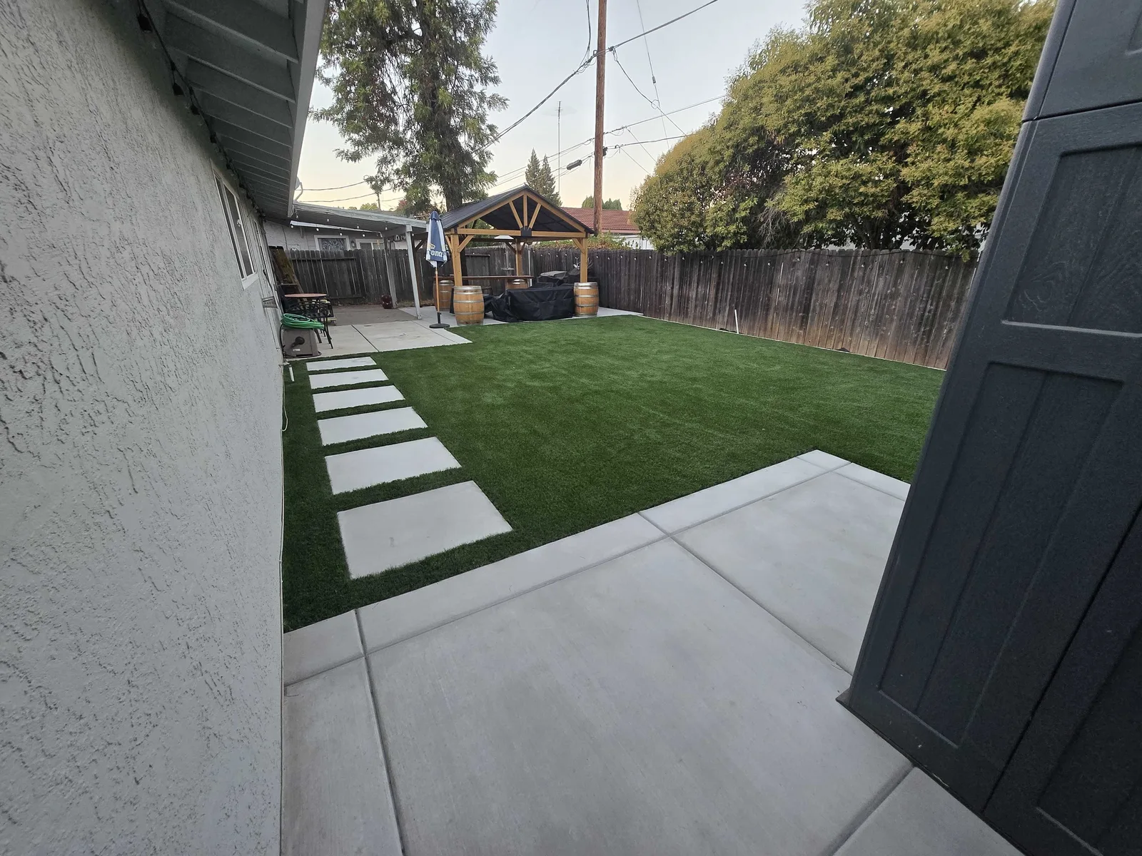 Artificial turf lawn with concrete stepping pads leading to a covered patio