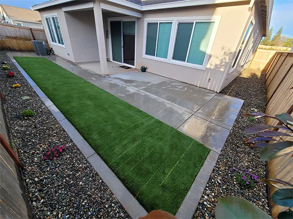 Turf lawn and concrete walkway bordered by planted flower beds
